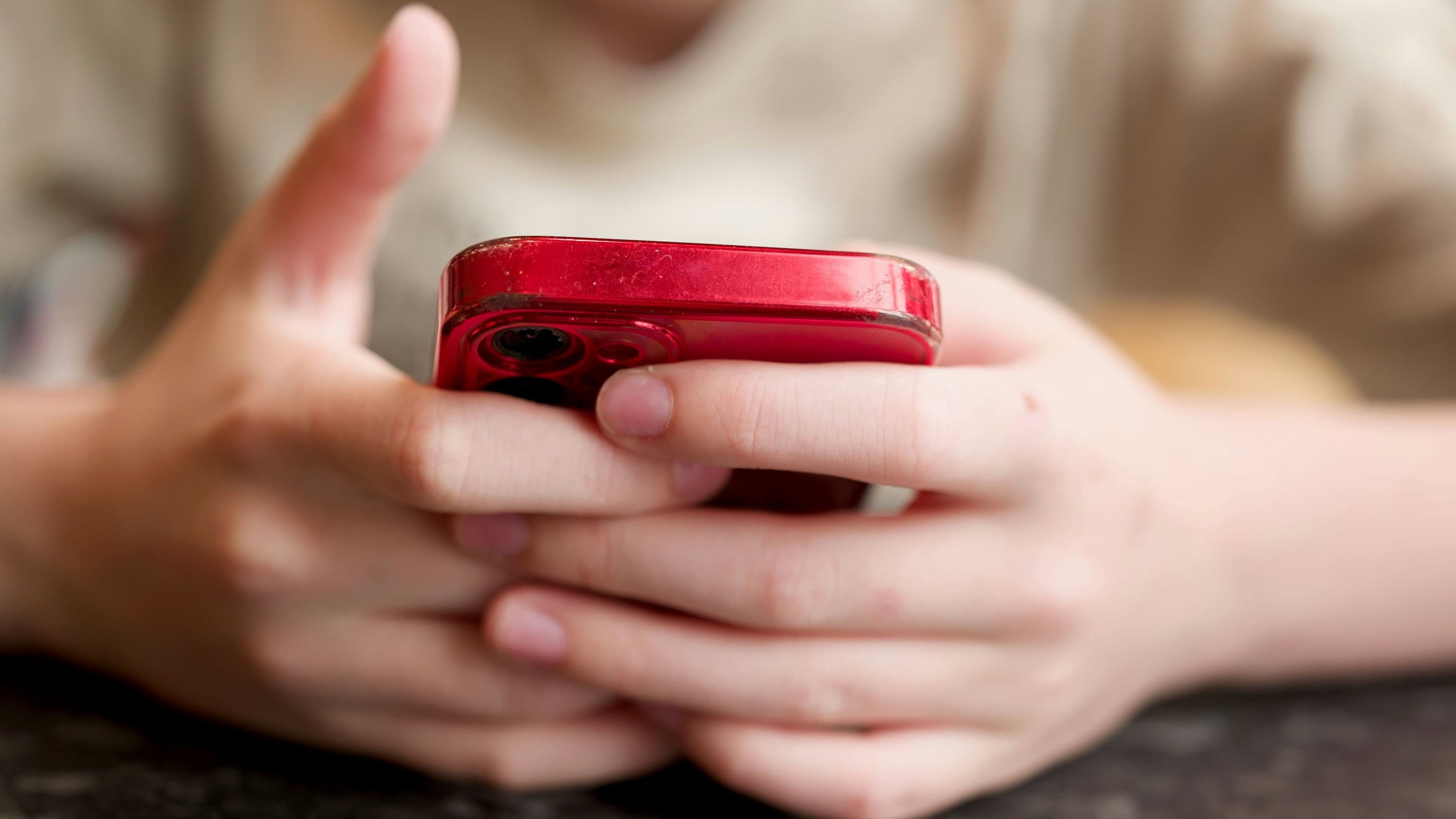 Junge Person hält ein Smartphone als Symbol für Altersprüfung und Jugendschutz im Netz