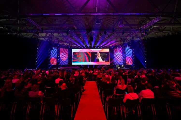 Große DMEXCO-Bühne mit farbiger Lichtshow vor dicht besetztem Publikum in einer Messehalle.