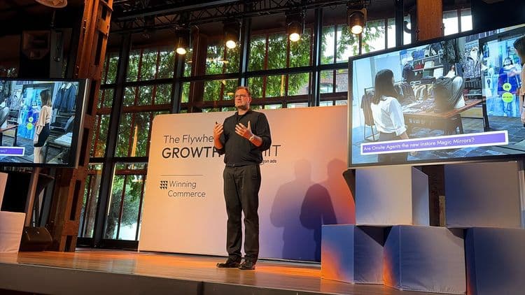 E-Commerce-Unternehmer Alexander Graf spricht auf der Bühne des Flywheel Growth Summit in Düsseldorf vor einer Präsentation zu Onsite Agents und Instore Magic Mirrors.