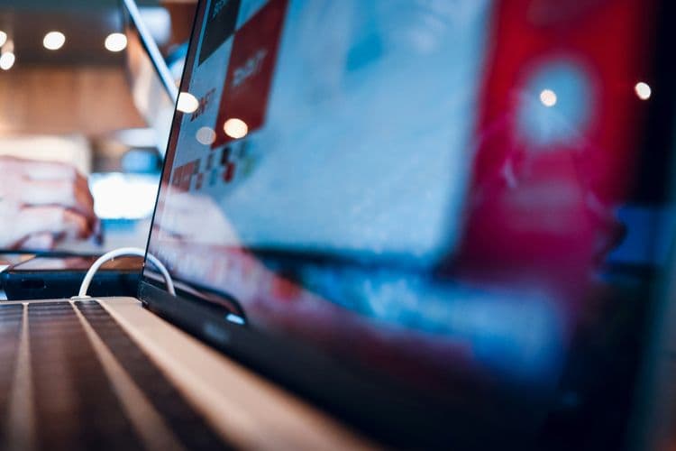 Nahaufnahme eines aufgeklappten Laptops mit spiegelndem Bildschirm in einer modernen Arbeitsumgebung.