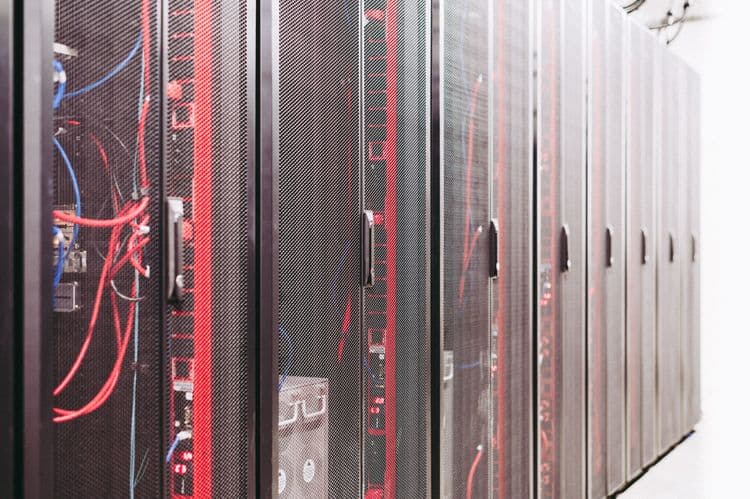 Serverracks in einem Rechenzentrum mit roten Leuchtelementen und sichtbaren Kabeln.