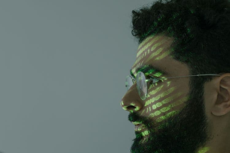 Mann mit Brille, auf dessen Gesicht grüne Lichtmuster projiziert werden.