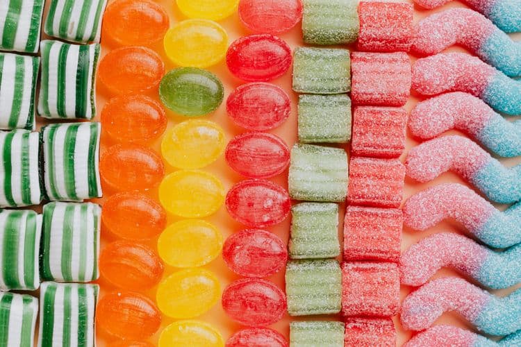 Verschiedene farbige Süßigkeiten sind nach Form und Farbe in Reihen angeordnet.