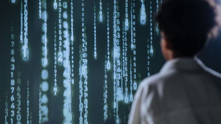 Person betrachtet eine Wand aus digitalen Zahlen als Symbol für Datenverarbeitung und Cloud-Kosten.