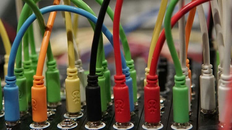 Mehrere farbige Kabel sind in eine technische Anschlussleiste eingesteckt.