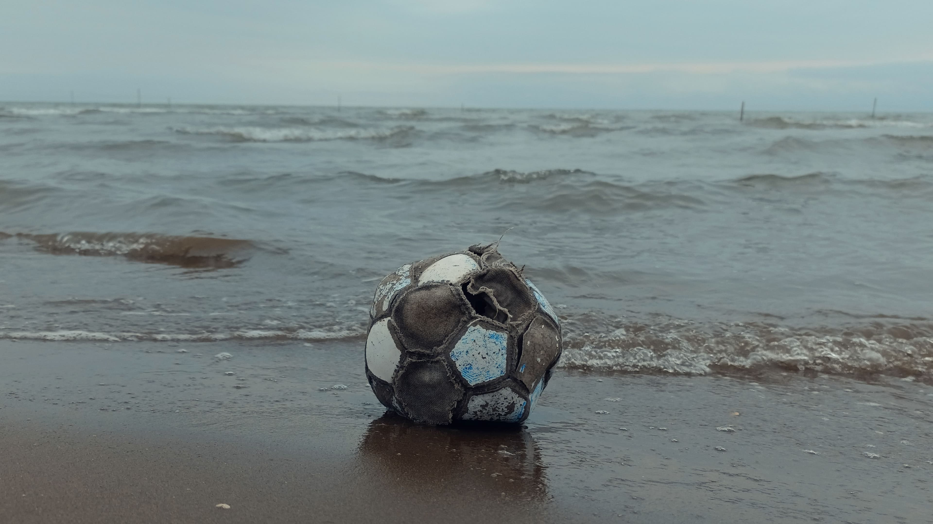 Kaputter Fußball am Ufer als Symbol für einen geplatzten WM-Traum.