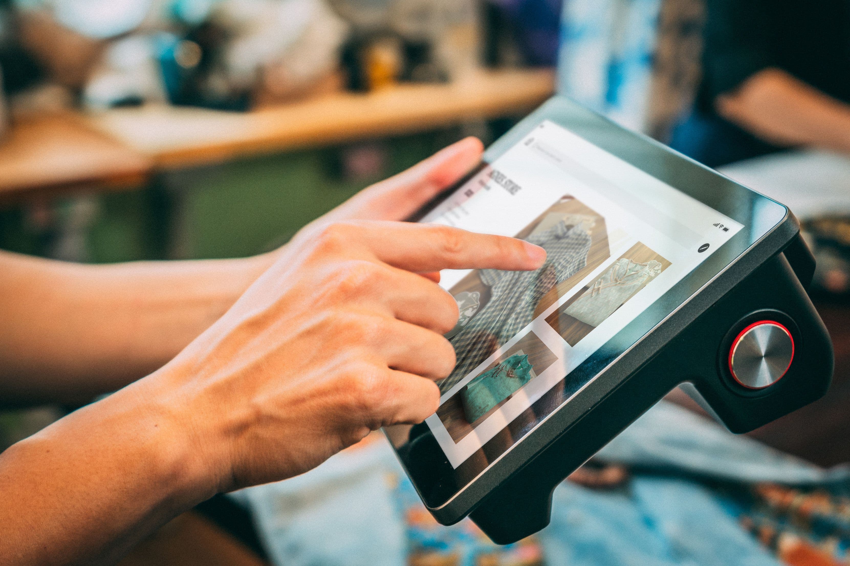 Person navigiert auf einem Touchscreen durch eine digitale Produktauswahl.