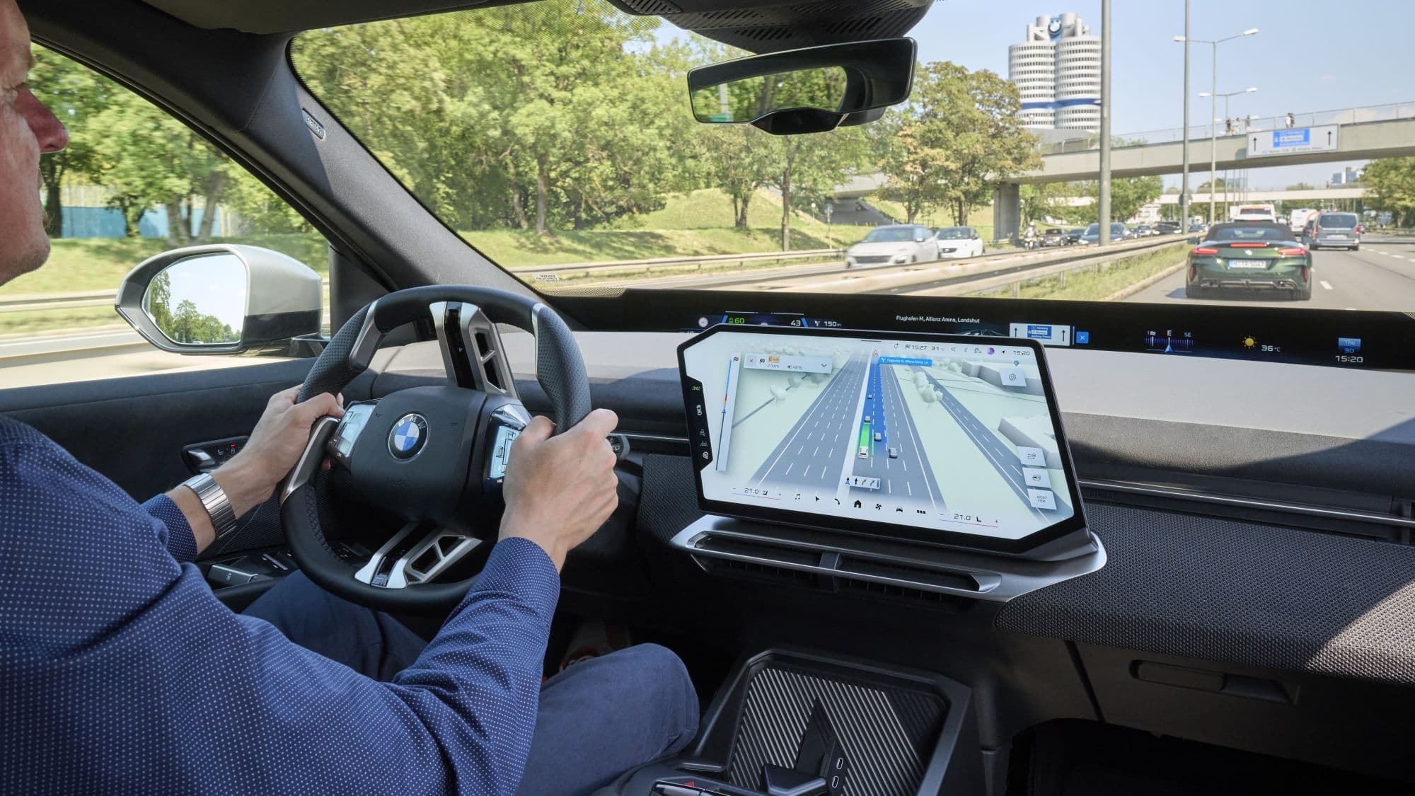 BMW-Fahrer vor digitalem Cockpit mit 3D-Navigation und Fahrerassistenzanzeige.