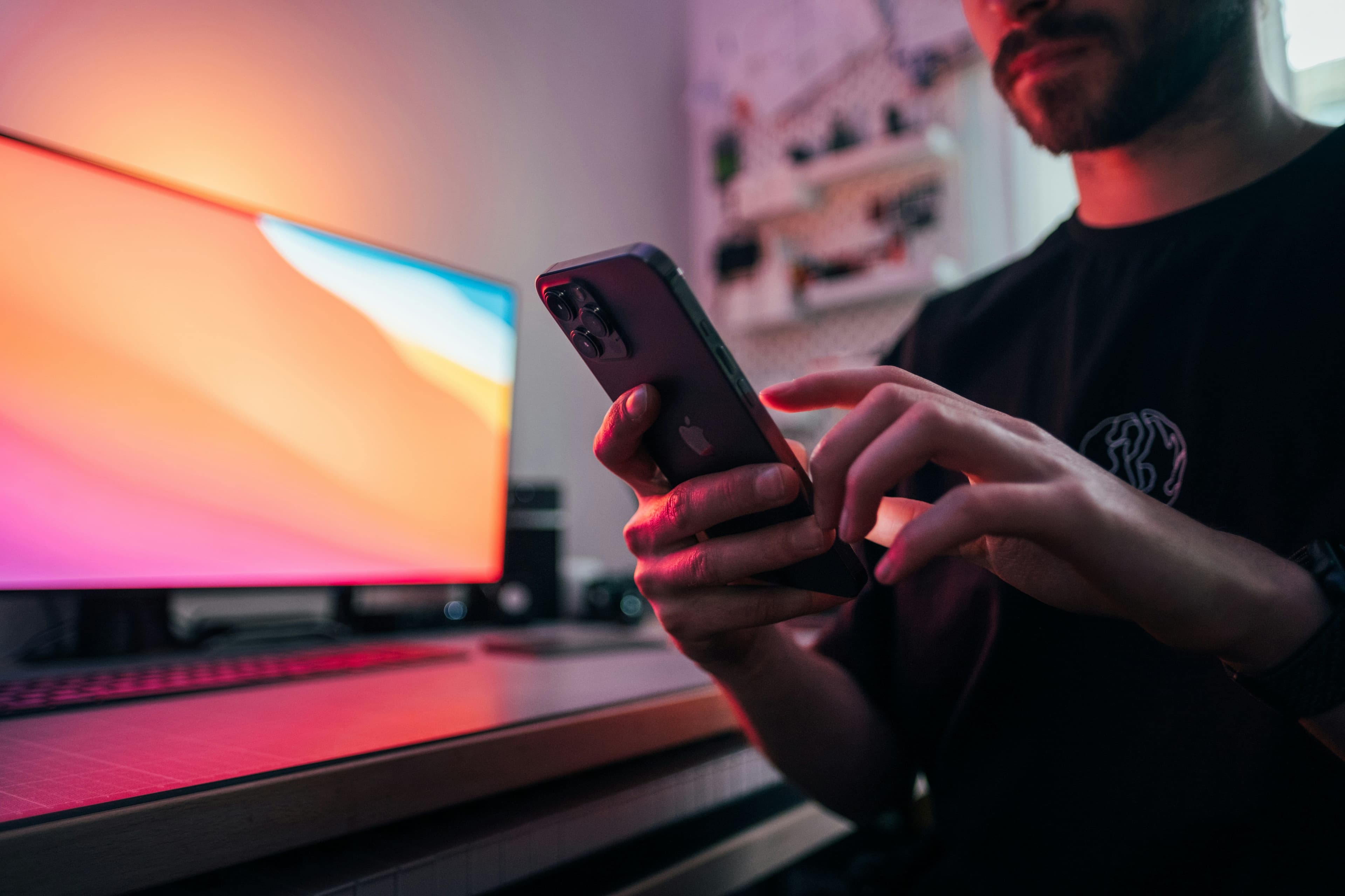 Eine Person am Smartphone mit neonfarbenem Bildhintergrund.