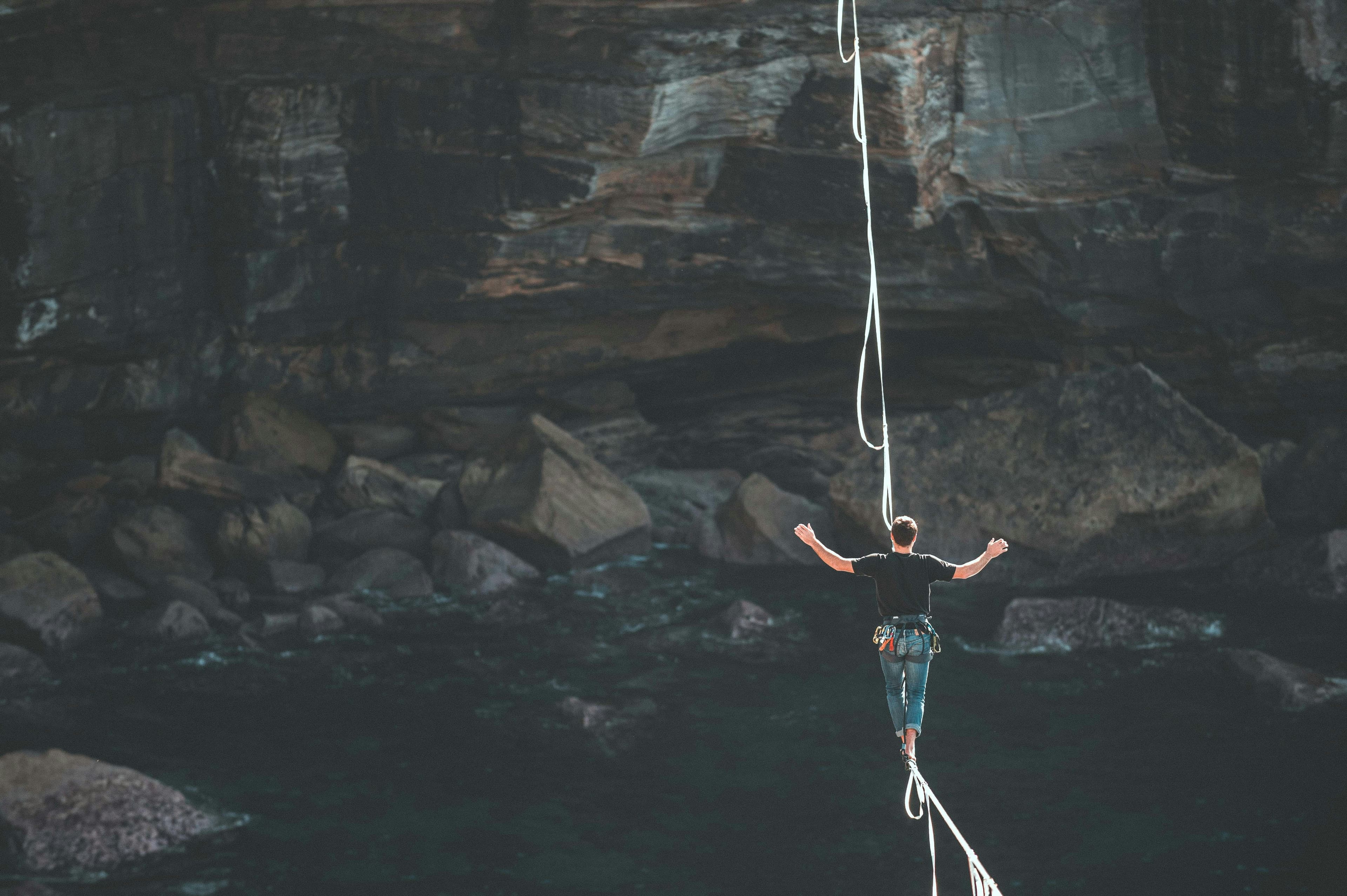 Ein Mann balanciert auf einem Hochseil über einem Canyon.