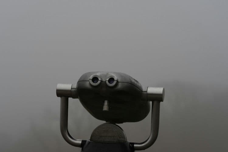 Graues Fernrohr in dichtem Nebel, frontal fotografiert, isoliert vor verschwommenem Hintergrund.