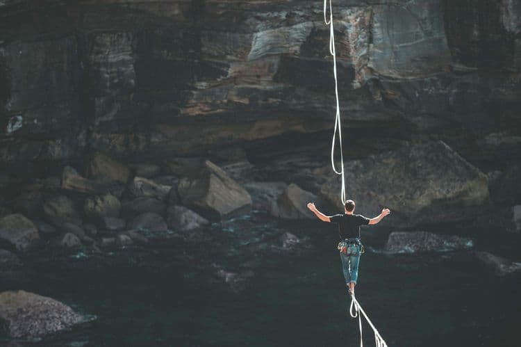 Ein Mann balanciert auf einem Hochseil über einem Canyon.