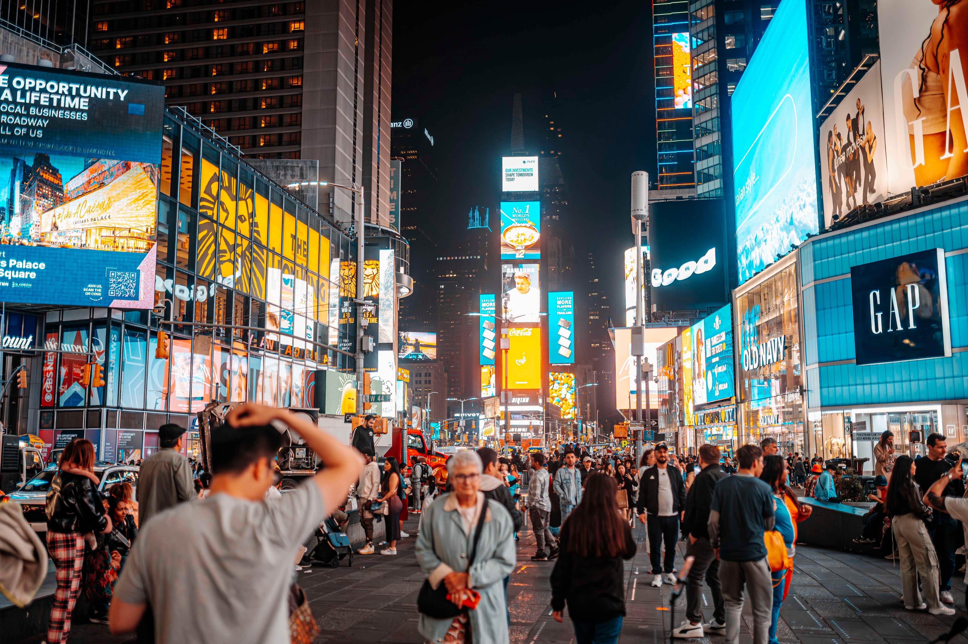 Menschen auf dem Times Square in New York zwischen zahlreichen großformatigen digitalen Werbescreens.
