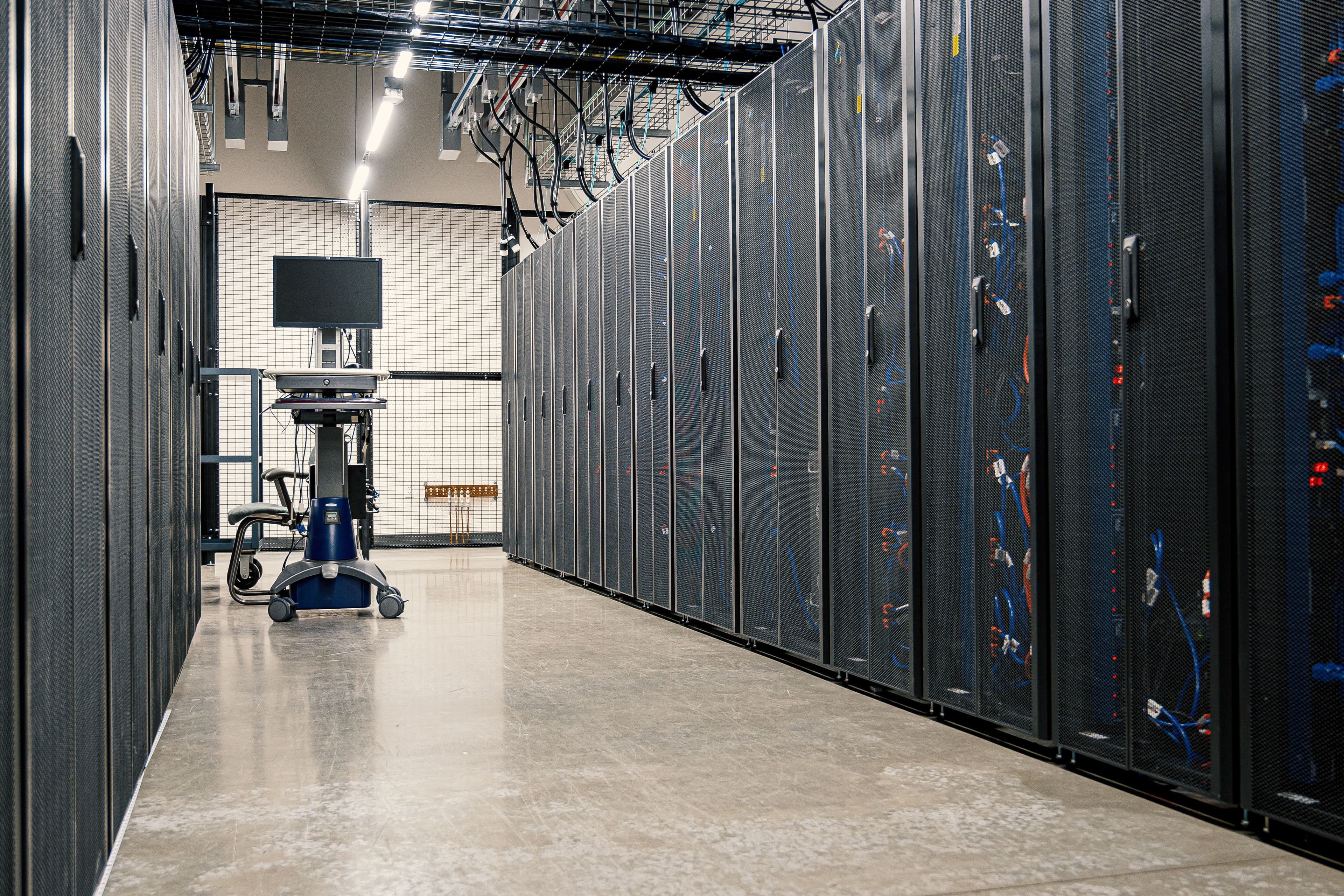 Serverracks in einem Rechenzentrum mit technischem Arbeitsplatz im Hintergrund.