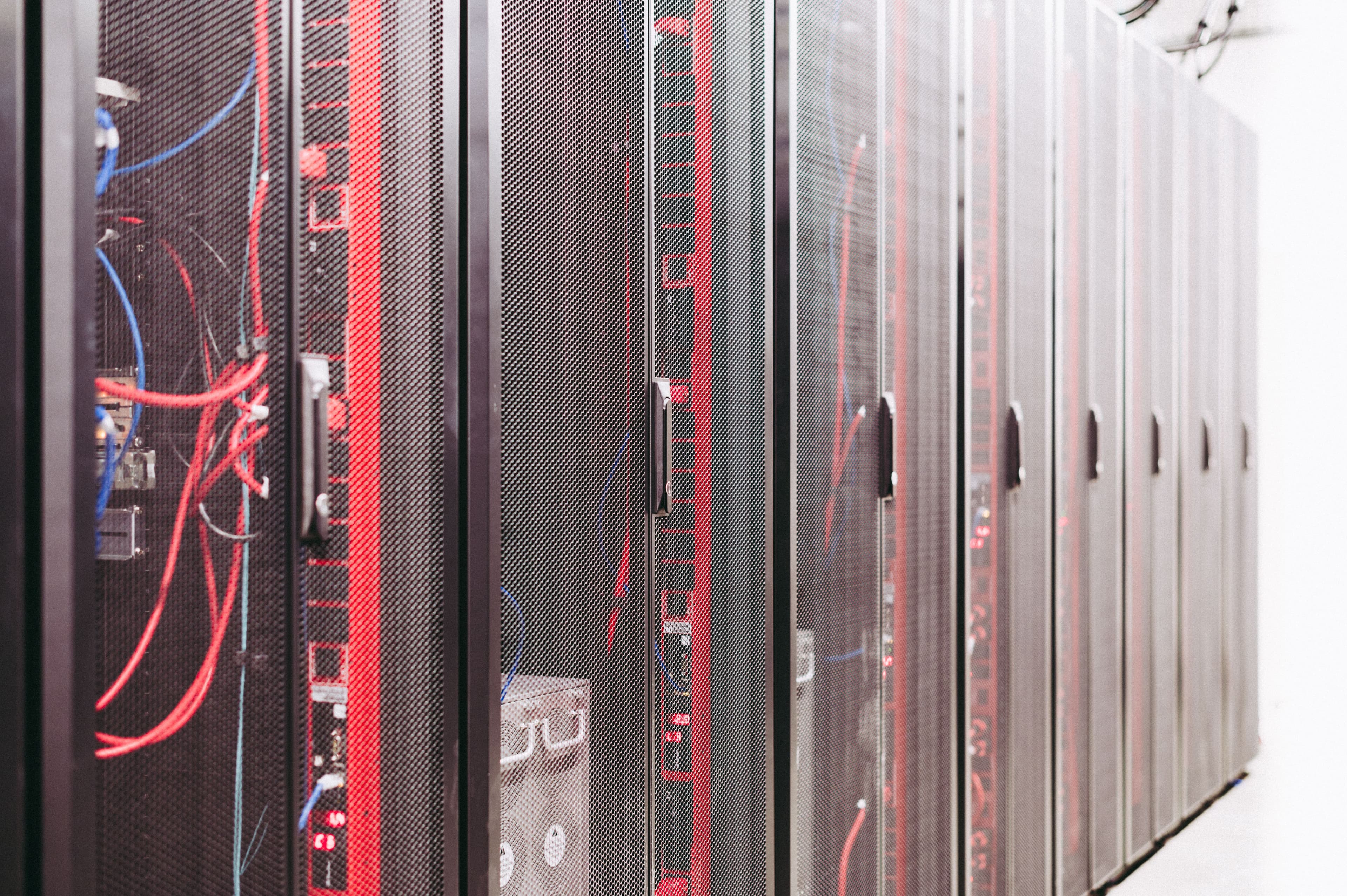 Serverracks in einem Rechenzentrum mit roten Leuchtelementen und sichtbaren Kabeln.