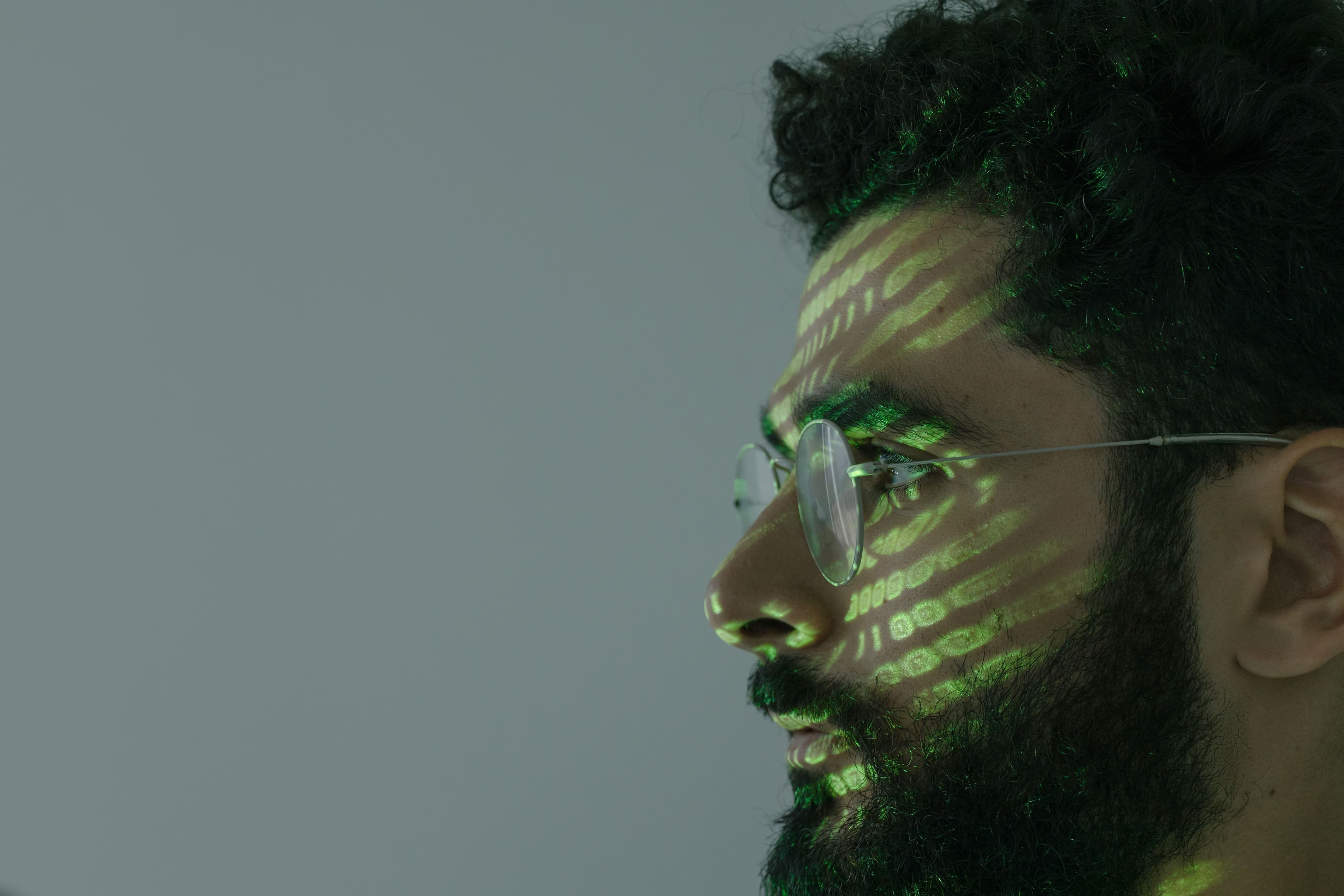 Mann mit Brille, auf dessen Gesicht grüne Lichtmuster projiziert werden.