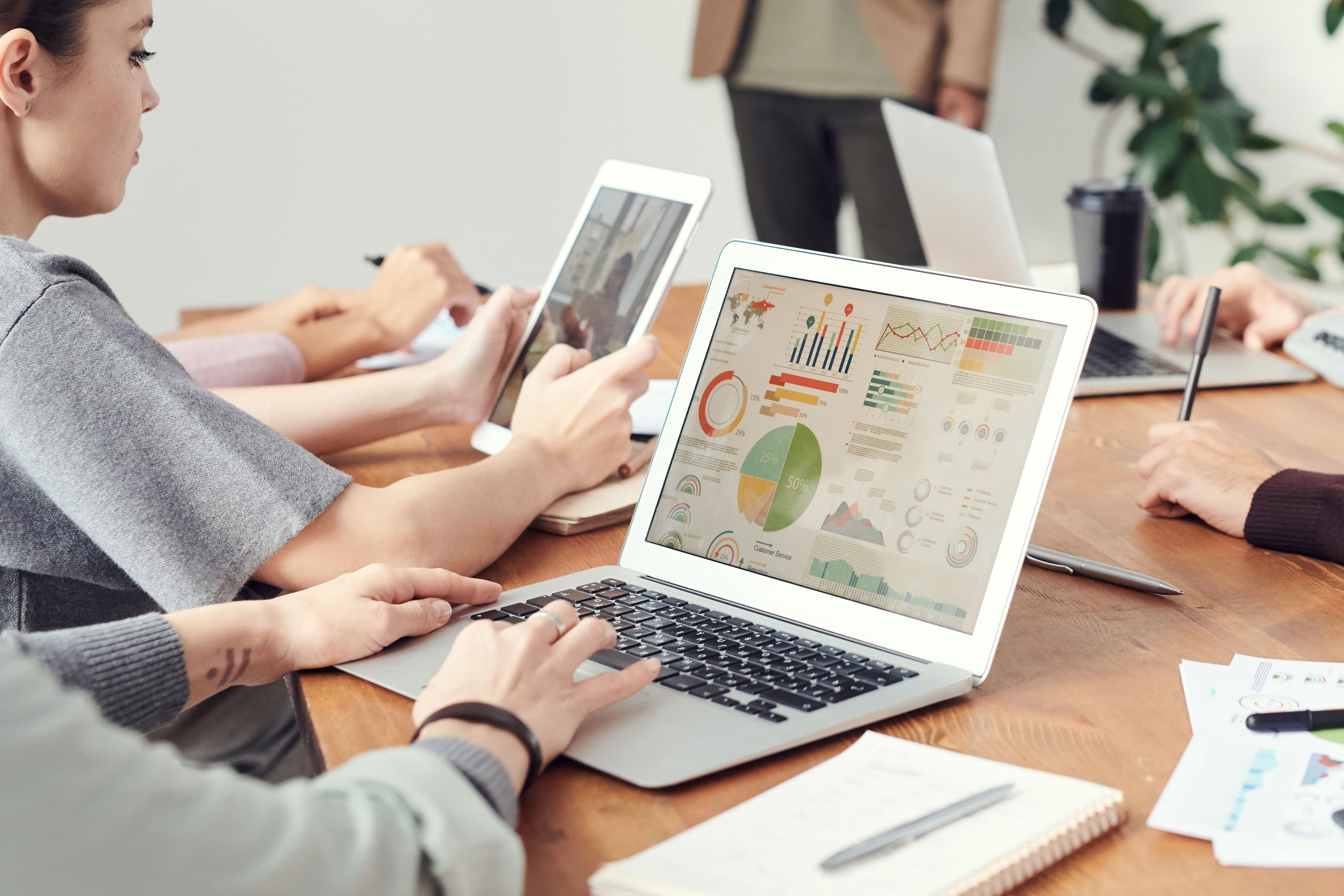 Personen arbeiten gemeinsam an einem Laptop mit Diagrammen und Datenauswertungen.