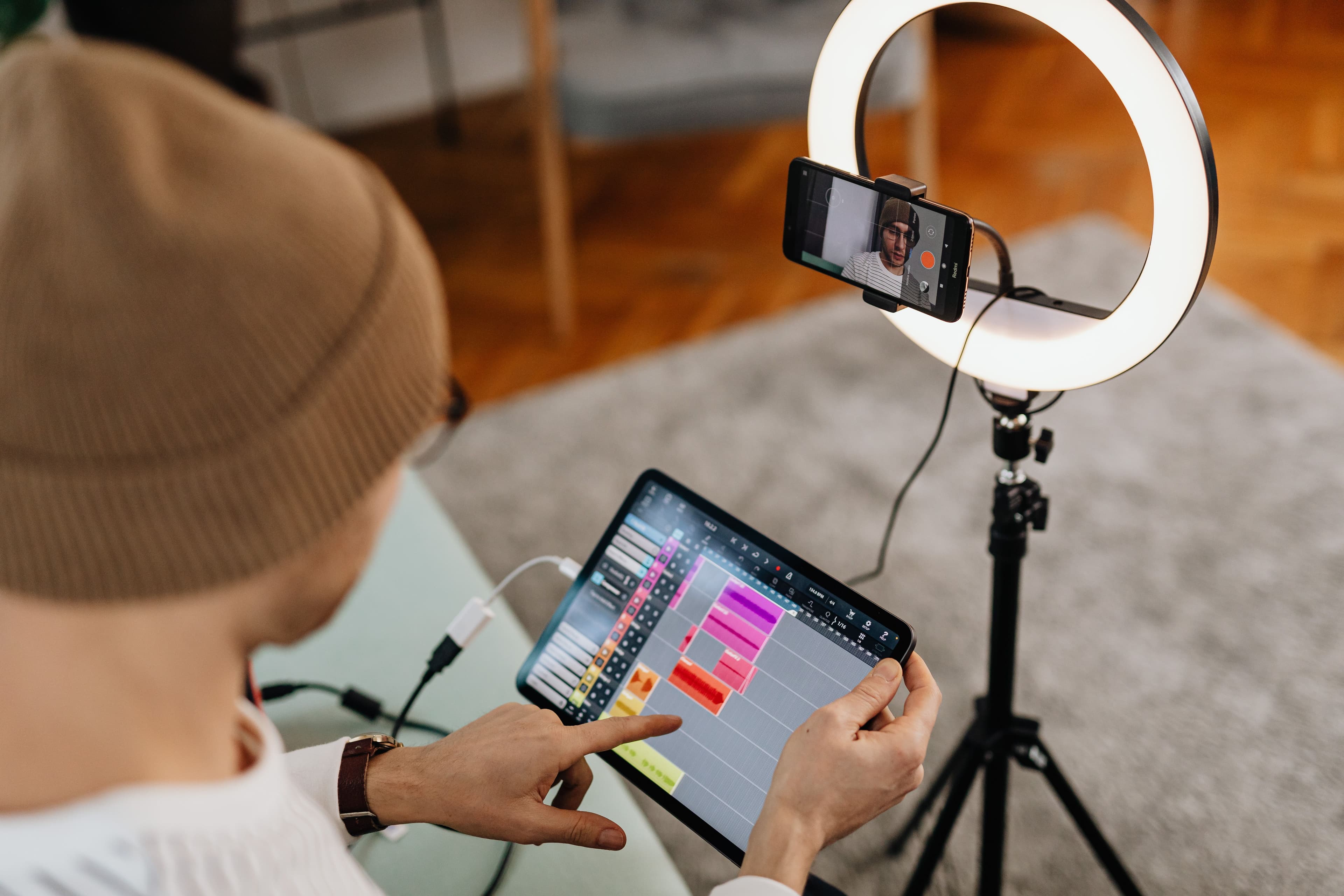 Creator filmt sich mit Smartphone und Ringlicht, während auf einem Tablet eine Bearbeitungsoberfläche zu sehen ist.