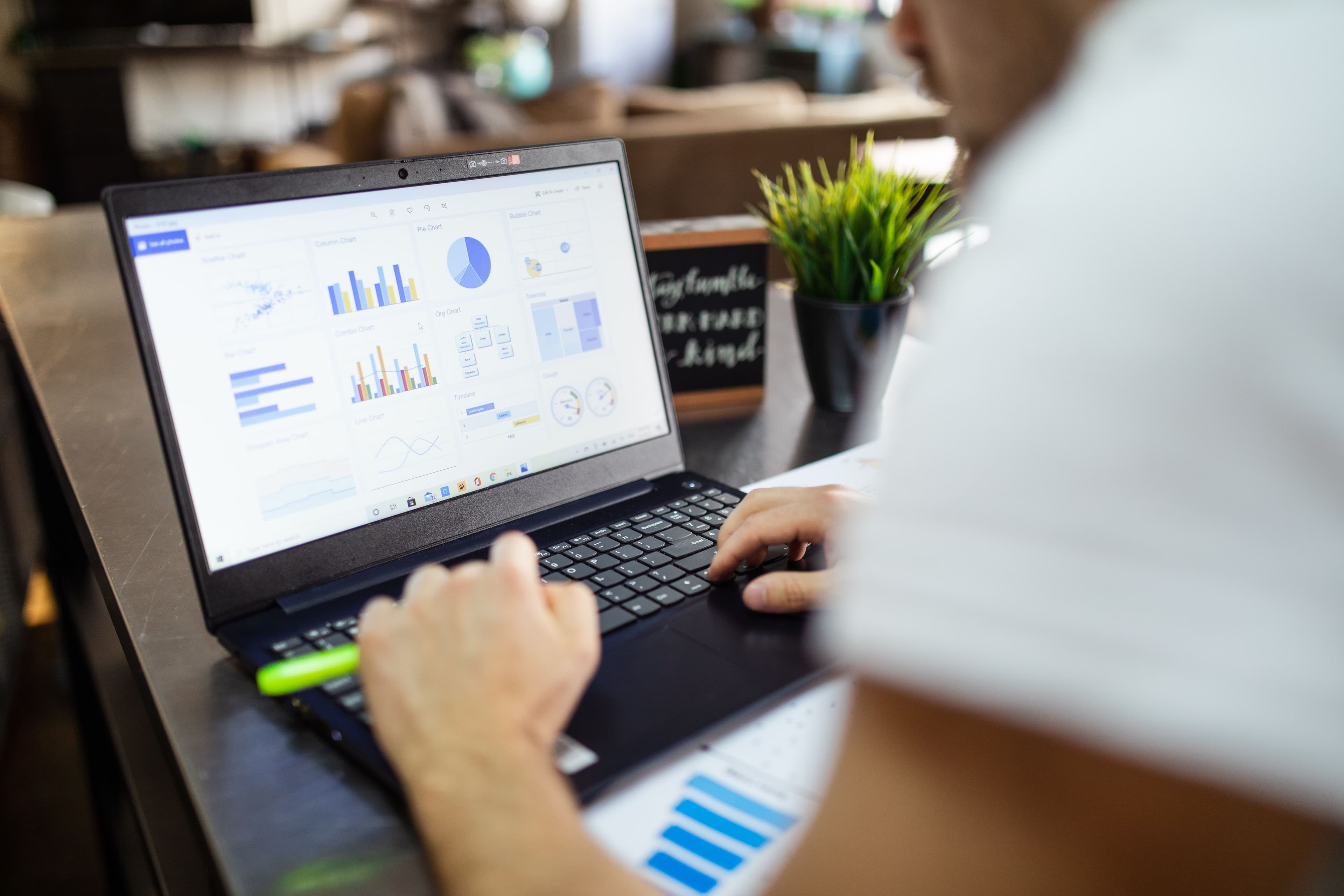 Person arbeitet an einem Laptop mit verschiedenen Diagrammen und Datenauswertungen.