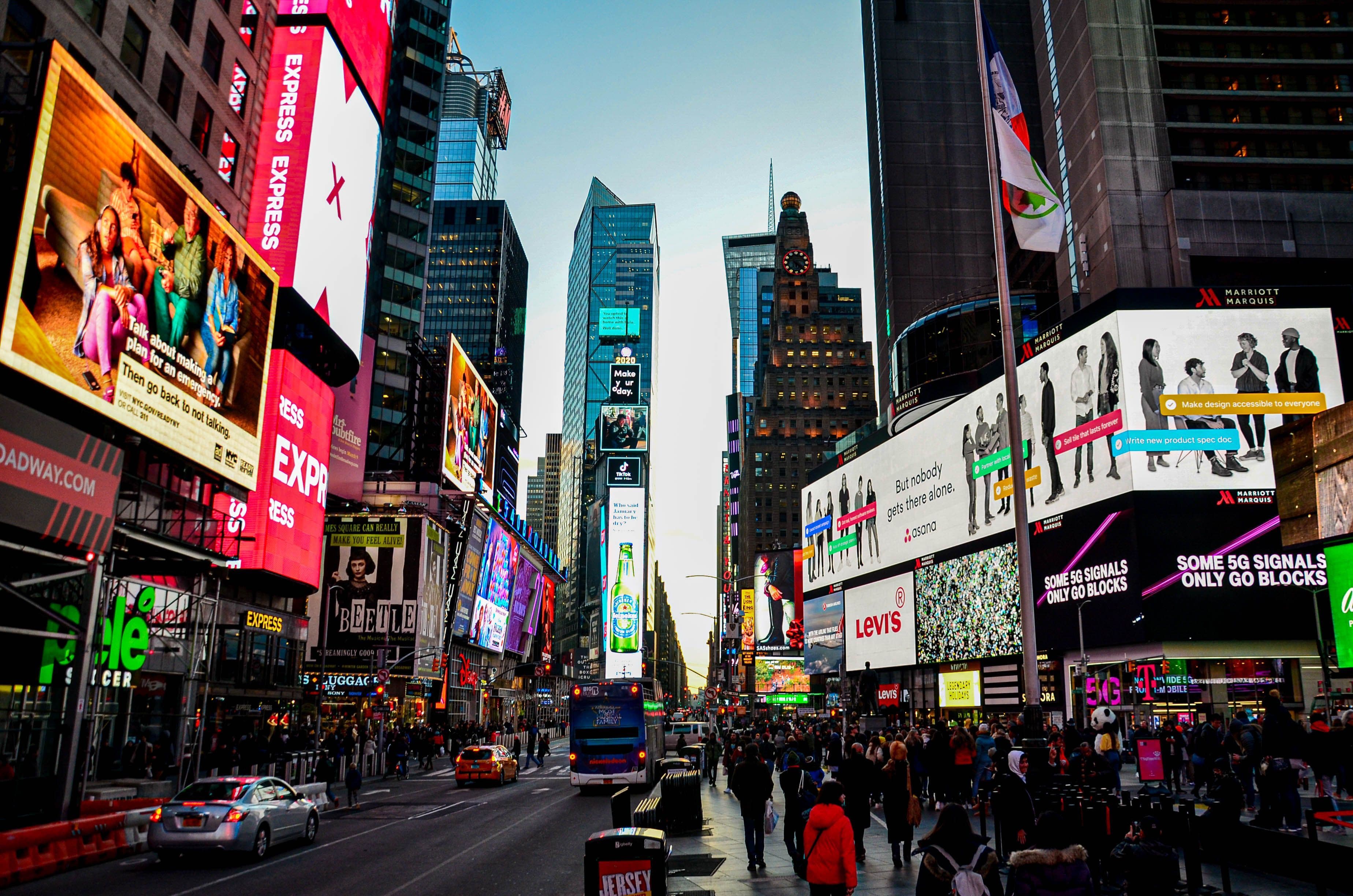 Times Square in New York mit zahlreichen digitalen Werbeflächen und Passanten.