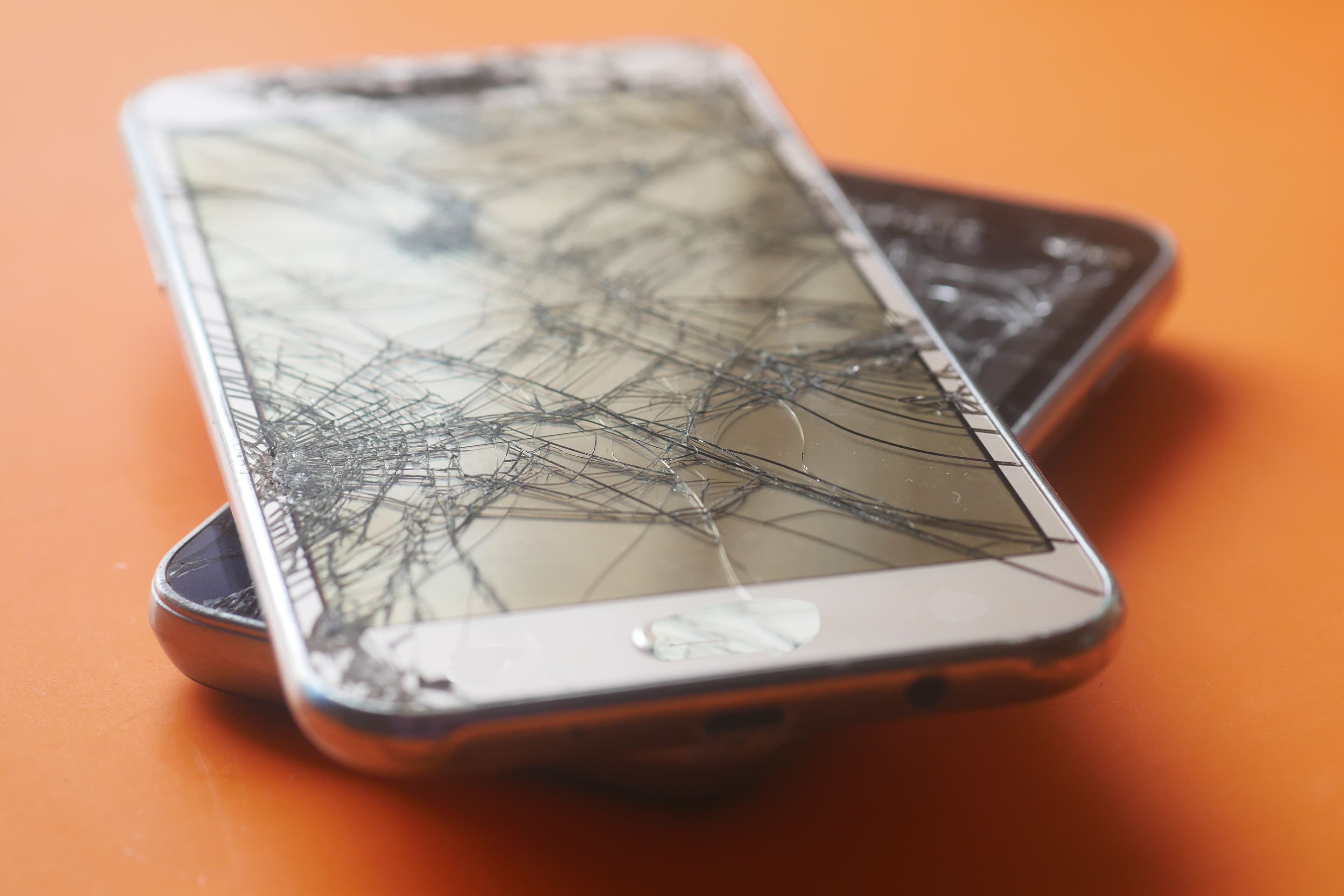 Smartphone mit stark gesprungenem Display auf einer Oberfläche.